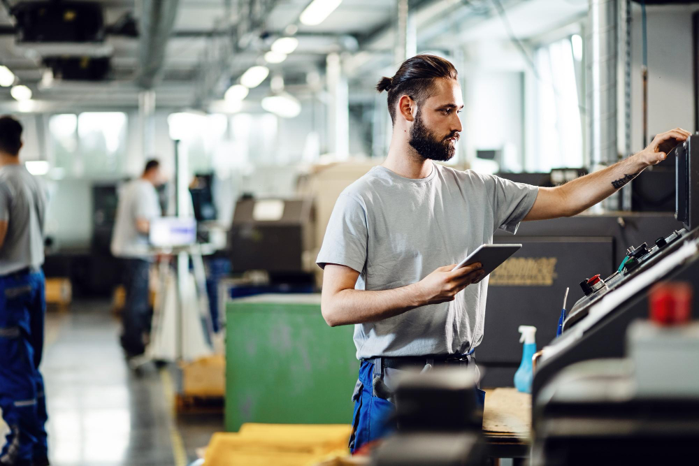 Profesional consulta una tablet junto al panel de control de una planta industrial